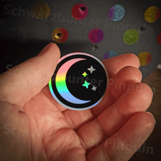 Celestial Moon Sticker mit Mond und Sternen in schwarz und Holo Optik. Auf dem Foto wird der Sticker in der Hand gehalten.
